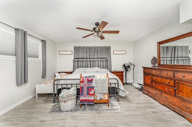 bedroom featuring a ceiling fan, light wood-style flooring, and baseboards