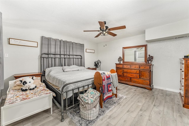 bedroom featuring light wood-style floors, a textured ceiling, baseboards, and a ceiling fan