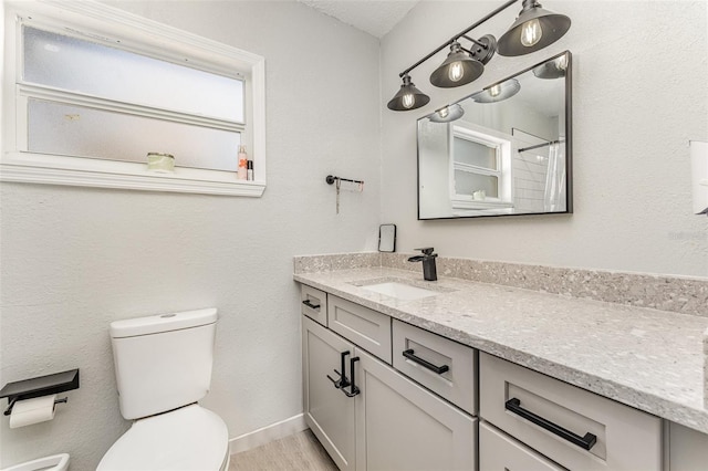 bathroom with wood finished floors, vanity, toilet, and baseboards