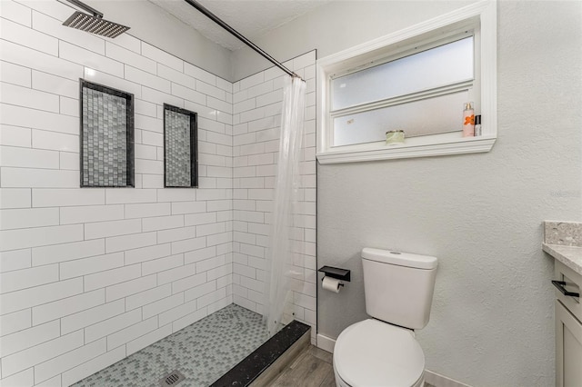 bathroom with toilet, a stall shower, a textured ceiling, vanity, and wood finished floors