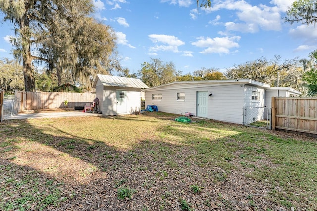 back of property with a fenced backyard, an outdoor structure, a lawn, a gate, and a shed