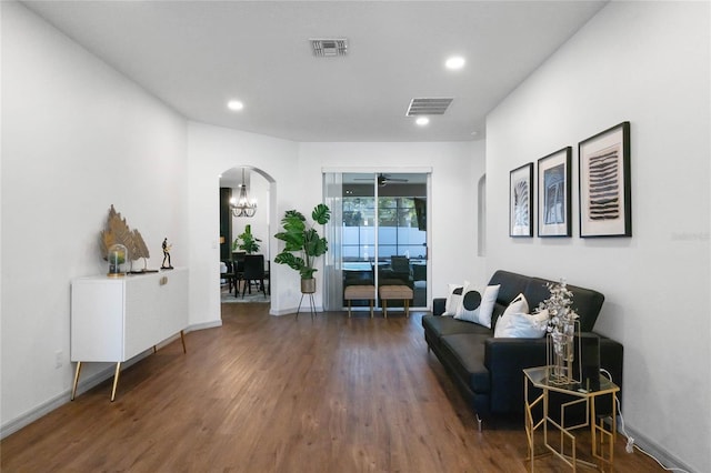 sitting room with an inviting chandelier, visible vents, arched walkways, and wood finished floors