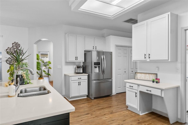 kitchen with arched walkways, a sink, visible vents, light countertops, and stainless steel refrigerator with ice dispenser