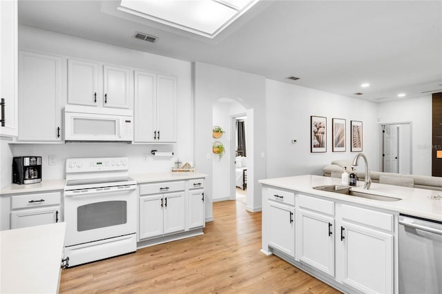 kitchen with arched walkways, visible vents, a sink, light wood-type flooring, and white appliances