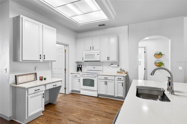 kitchen with white appliances, visible vents, arched walkways, light countertops, and a sink