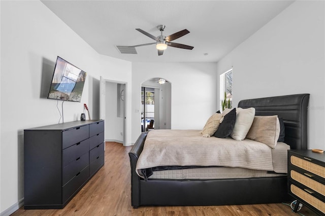 bedroom with arched walkways, multiple windows, wood finished floors, and visible vents