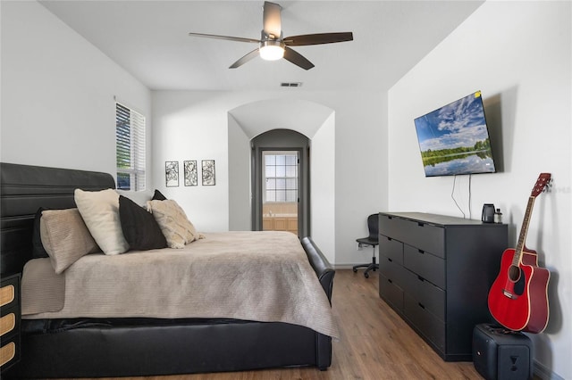 bedroom with a ceiling fan, visible vents, ensuite bath, and wood finished floors