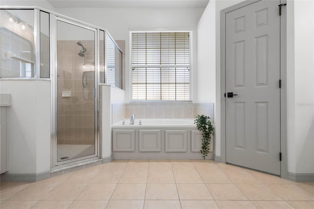 bathroom featuring tile patterned flooring, a garden tub, and a shower stall