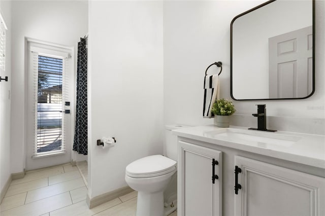 bathroom with tile patterned flooring, baseboards, vanity, and toilet