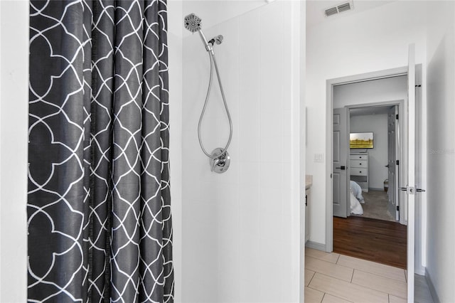 full bathroom featuring visible vents, a tile shower, vanity, and wood finished floors