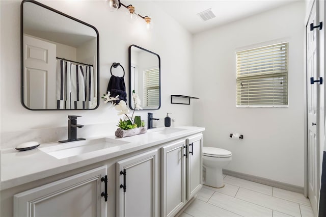 full bath with visible vents, a sink, toilet, and double vanity