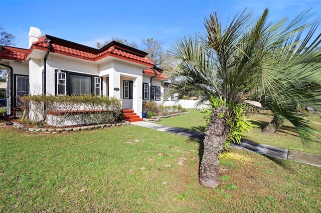 mediterranean / spanish home featuring a tiled roof, a front lawn, and stucco siding