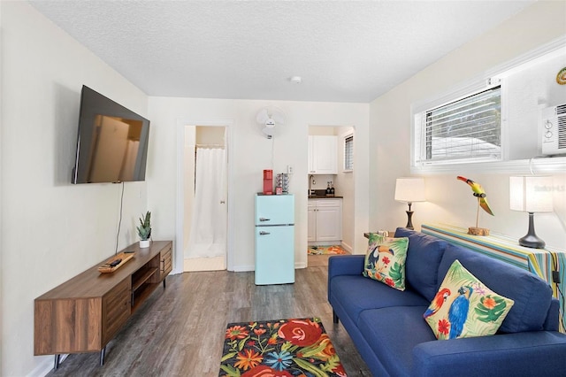 living area featuring a textured ceiling, baseboards, and wood finished floors