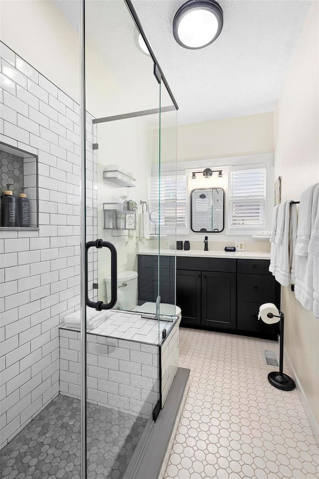 bathroom featuring a shower stall, baseboards, a textured ceiling, and vanity