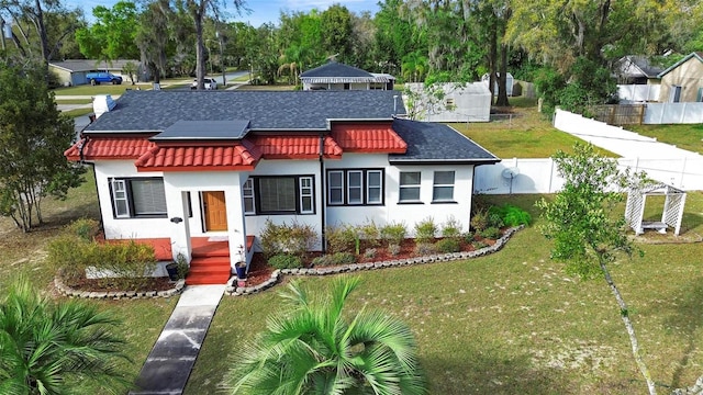 view of front of home with roof with shingles, a front yard, fence, and stucco siding