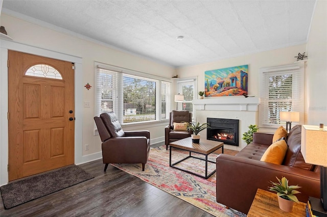 living area with a textured ceiling, wood finished floors, a fireplace with flush hearth, and baseboards