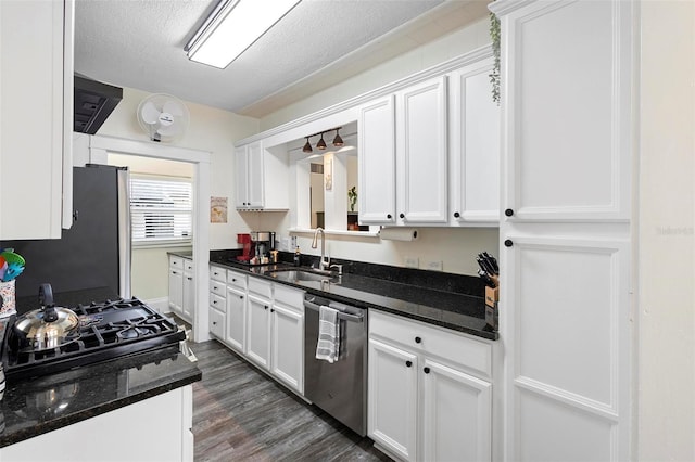 kitchen with a textured ceiling, appliances with stainless steel finishes, white cabinets, and a sink