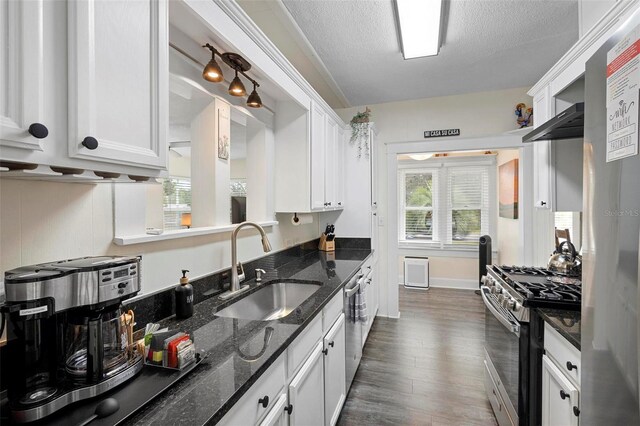 kitchen featuring stainless steel appliances, dark wood-type flooring, white cabinetry, a sink, and a textured ceiling