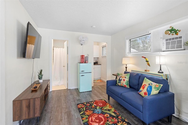 living area with a textured ceiling, baseboards, and wood finished floors