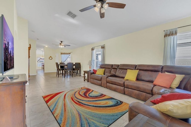 living area featuring light tile patterned floors, visible vents, and a ceiling fan