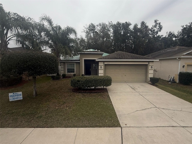 view of front facade with a garage, concrete driveway, a front yard, and stucco siding