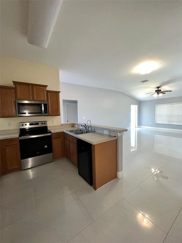 kitchen with appliances with stainless steel finishes, open floor plan, brown cabinets, and a peninsula