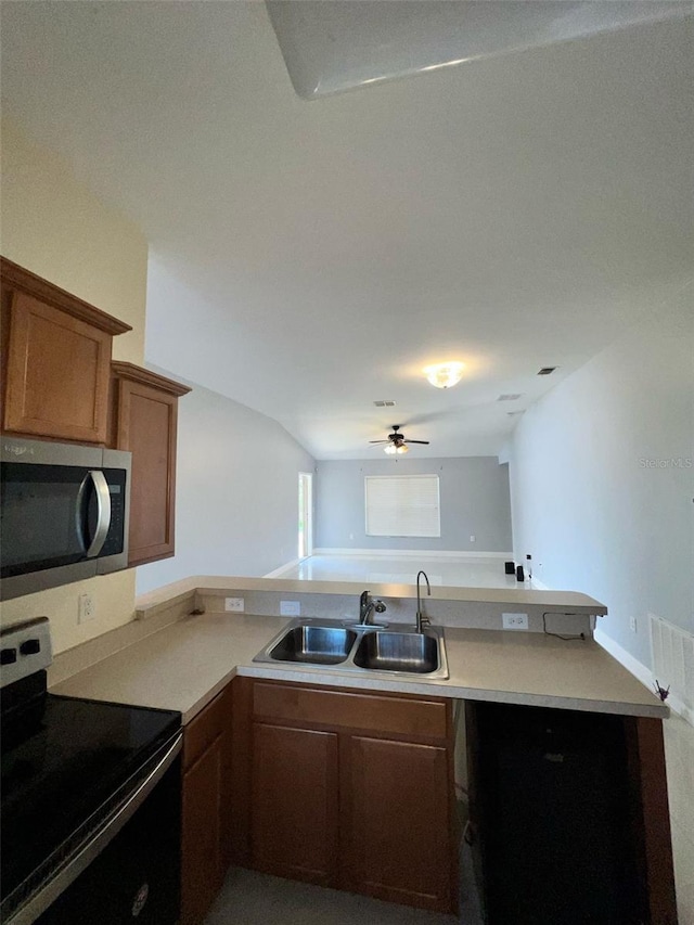 kitchen featuring appliances with stainless steel finishes, brown cabinets, a peninsula, light countertops, and a sink