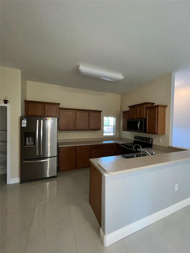 kitchen featuring light countertops, appliances with stainless steel finishes, light tile patterned flooring, a sink, and a peninsula