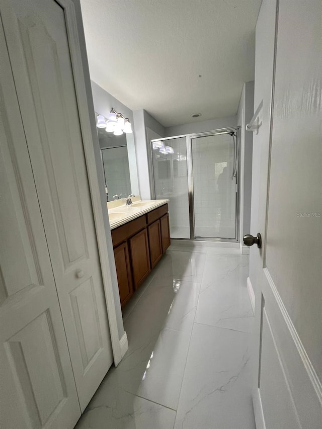 full bath featuring a textured ceiling, marble finish floor, a stall shower, and vanity