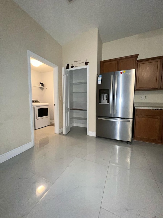 kitchen with marble finish floor, washer / clothes dryer, stainless steel fridge, and baseboards