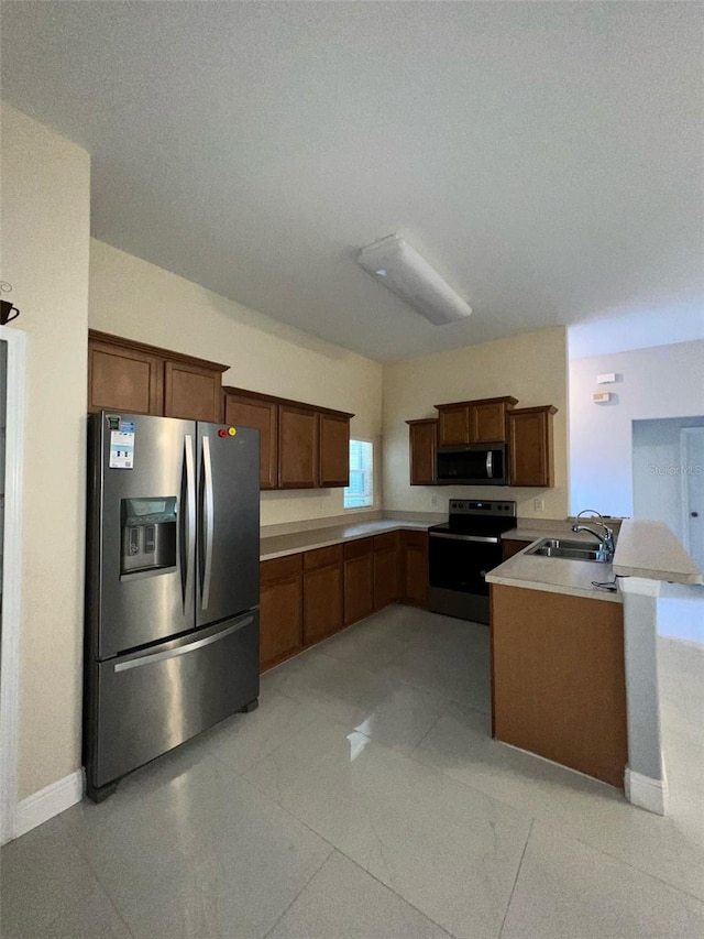 kitchen with light countertops, appliances with stainless steel finishes, a sink, a peninsula, and baseboards