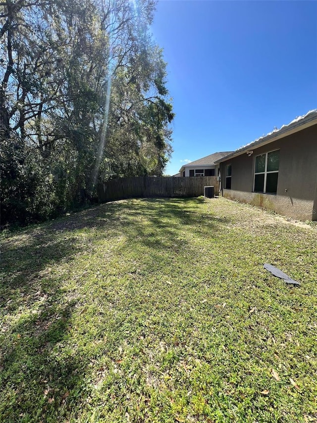 view of yard with fence and central AC