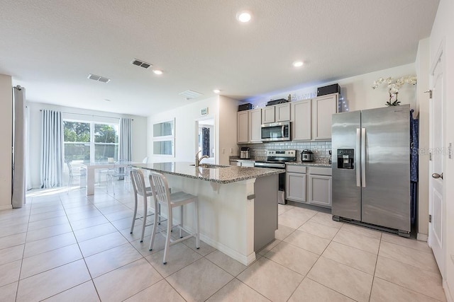 kitchen featuring stainless steel appliances, light tile patterned flooring, visible vents, and decorative backsplash