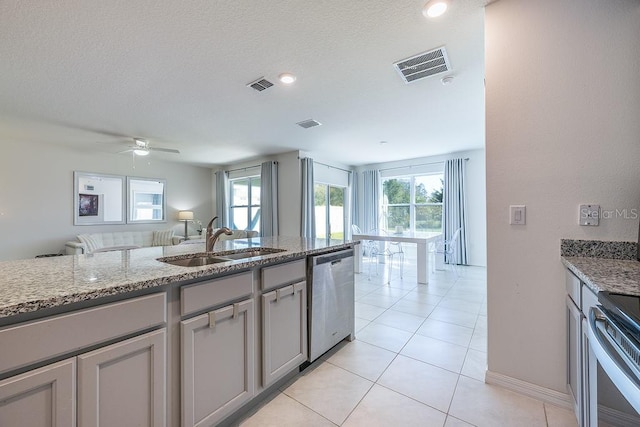 kitchen featuring stainless steel appliances, visible vents, a sink, and light stone countertops