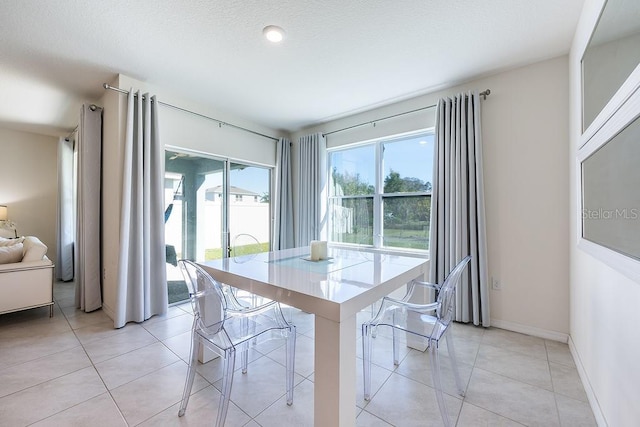 dining area with baseboards, a textured ceiling, and light tile patterned flooring