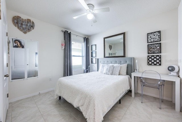 bedroom featuring light tile patterned floors, ceiling fan, a textured ceiling, and baseboards