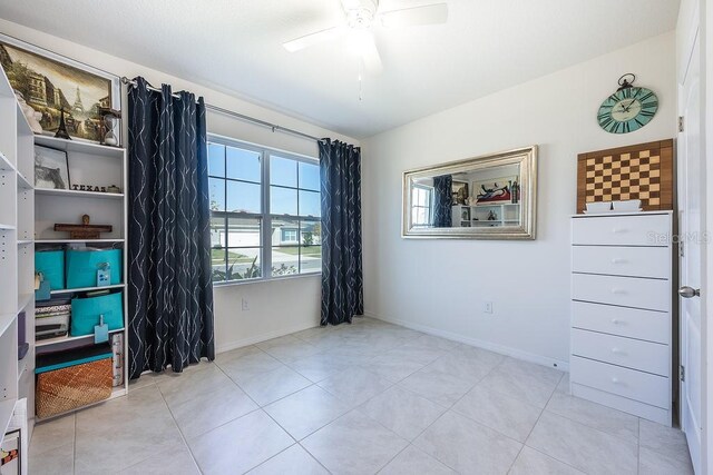 tiled spare room featuring a ceiling fan and baseboards