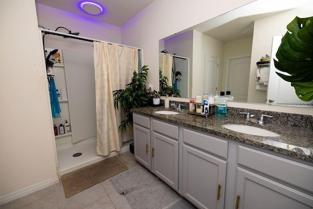 bathroom featuring a stall shower, tile patterned flooring, a sink, and double vanity