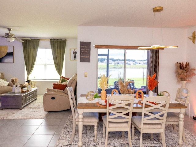 tiled dining area featuring a water view and ceiling fan