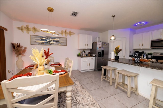 kitchen with light tile patterned floors, visible vents, appliances with stainless steel finishes, white cabinetry, and dark stone counters