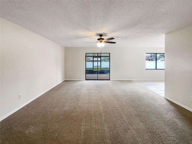 unfurnished room with a ceiling fan, carpet flooring, a textured ceiling, and baseboards