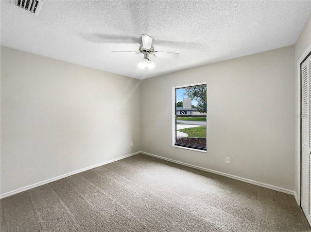 empty room with carpet, visible vents, and baseboards