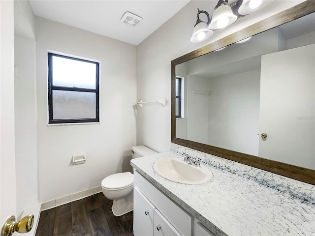 bathroom with visible vents, toilet, vanity, wood finished floors, and baseboards