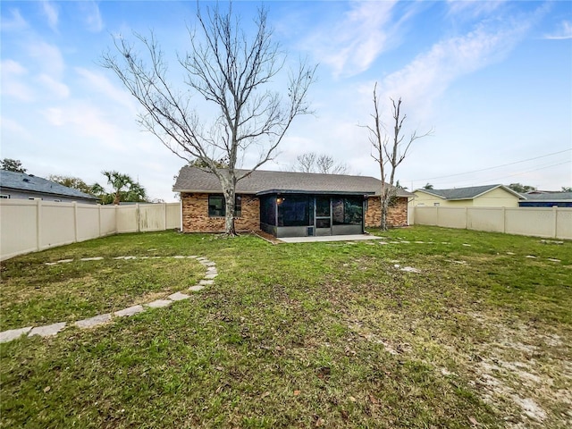 back of property featuring a yard, brick siding, a fenced backyard, and a sunroom