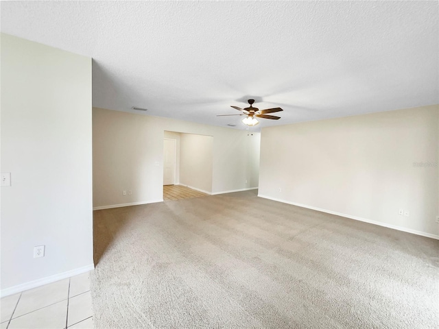 empty room with light carpet, a textured ceiling, baseboards, and a ceiling fan