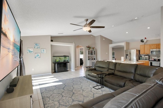 living room with arched walkways, light tile patterned flooring, lofted ceiling, and a textured ceiling