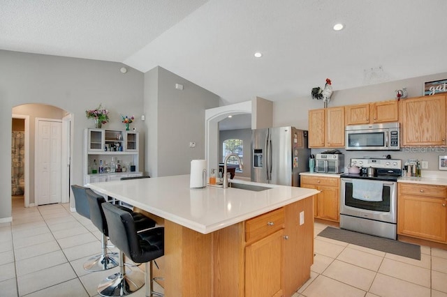 kitchen featuring lofted ceiling, arched walkways, stainless steel appliances, and a sink