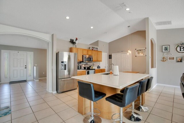 kitchen with arched walkways, light tile patterned flooring, stainless steel appliances, a sink, and visible vents