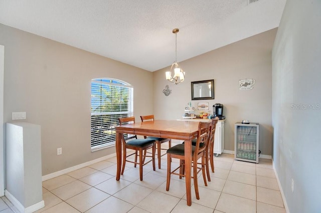 dining area with lofted ceiling, light tile patterned flooring, a textured ceiling, beverage cooler, and baseboards