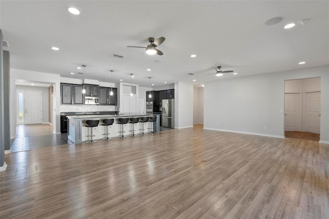 unfurnished living room featuring ceiling fan, light wood-type flooring, visible vents, and baseboards